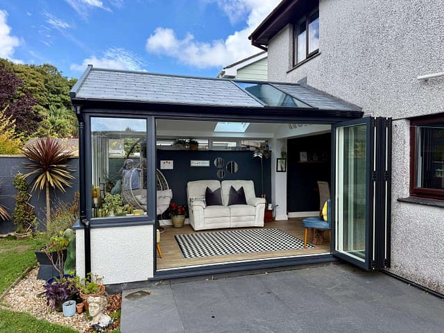 Renovated garden room with anthracite-grey frames and bifold doors fully open to the patio.