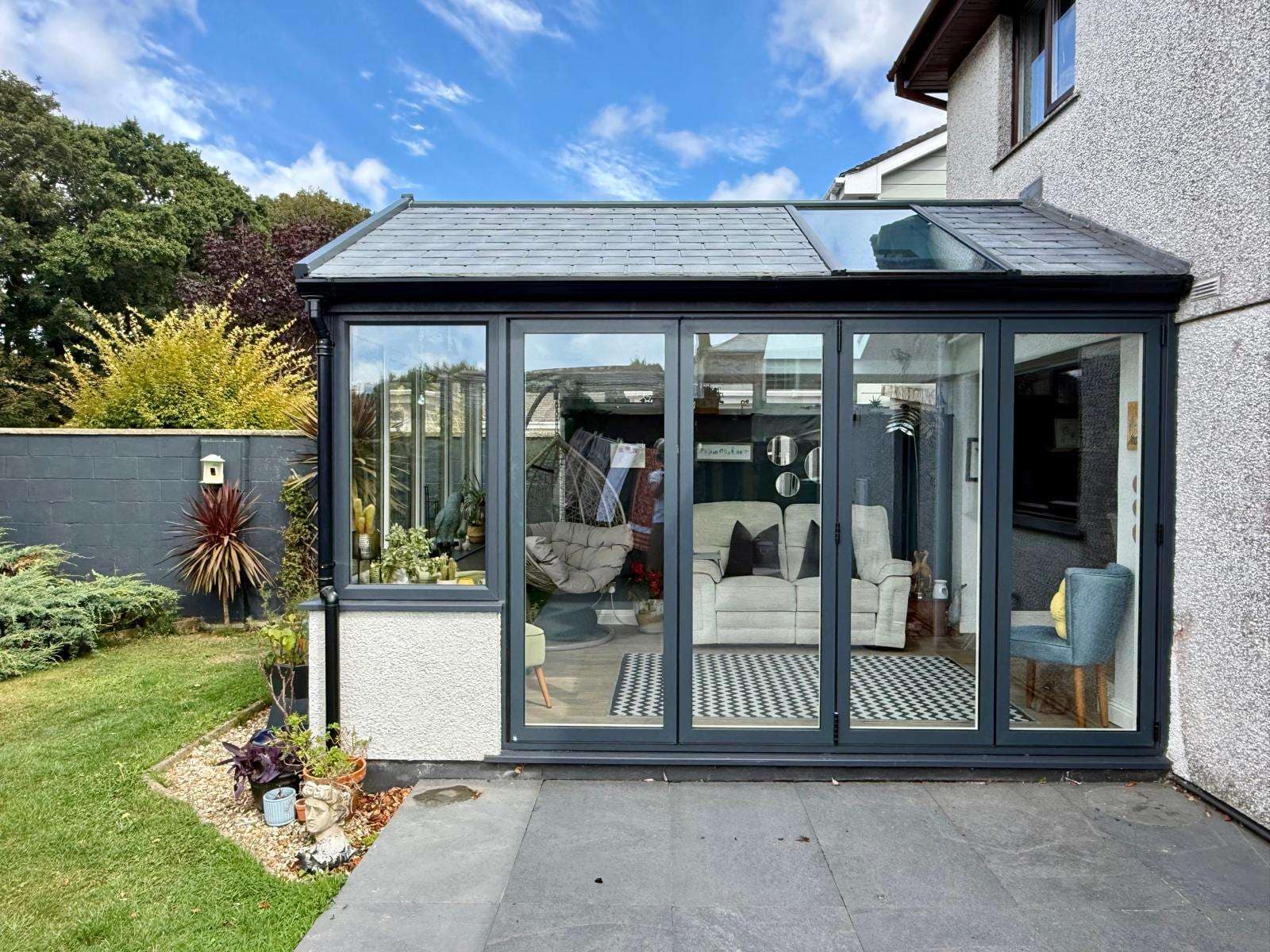 Completed anthracite-grey garden room with bifold doors overlooking a paved patio.