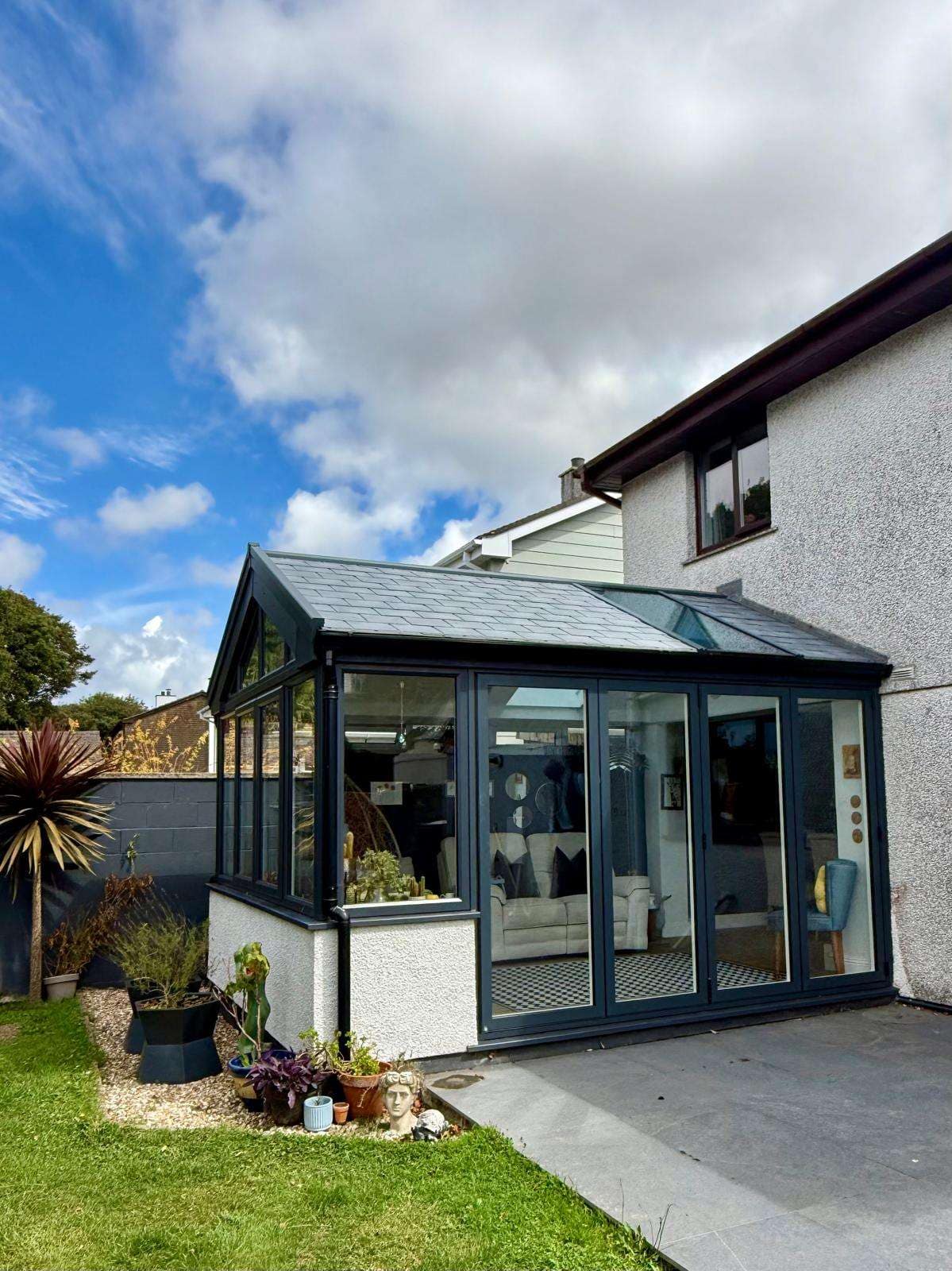 Exterior side view showing the slate-effect roof, glazed gable and anthracite-grey frames.